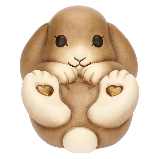 Brauner Hase der auf dem Rücken liegt. Auf den zwei hintern Pfoten die nach oben schauen sind zwei kleine Herzen