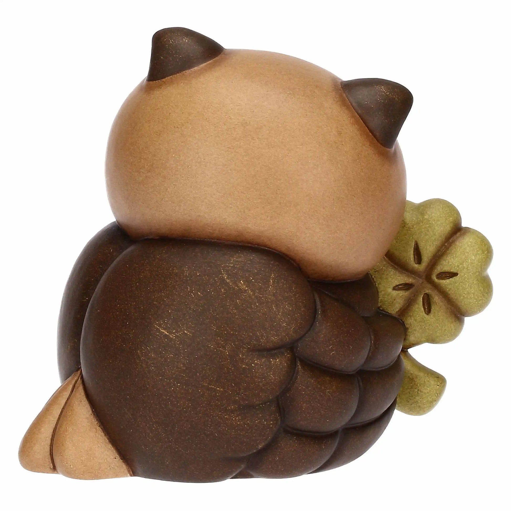 „Dekorative Eulenfigur aus Keramik, klein und handgemacht, hält ein vierblättriges Kleeblatt als Glückssymbol.“